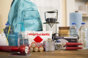 Emergency preparedness supplies. flashlight, backpack, batteries, water bottles, first aid kit, lantern, radio, can opener and mask.