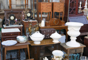 Items sit on a table at an estate sale. Older vases, pottery, and baking dishes.